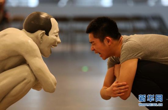 4月8日，在南京艺术学院美术馆，一名观众摆出与岳敏君作品同样的造型。新华社发 